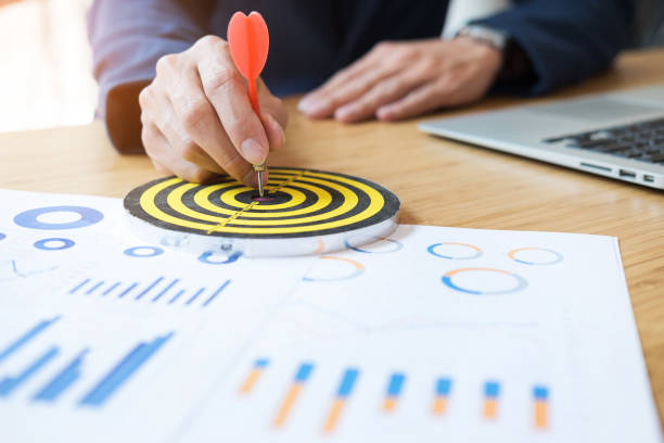 istock Midsection Of Businessman Aiming On Dartboard While Working At Desk In Office 910880398