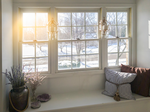 Photo taken inside a home showing a glass window . Snow and winter scene on outside.