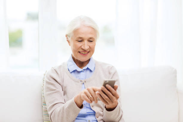 istock senior woman with smartphone texting at home 910902292