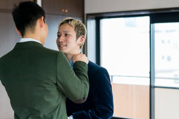 istock Young male couple helping each other to get ready 910906292