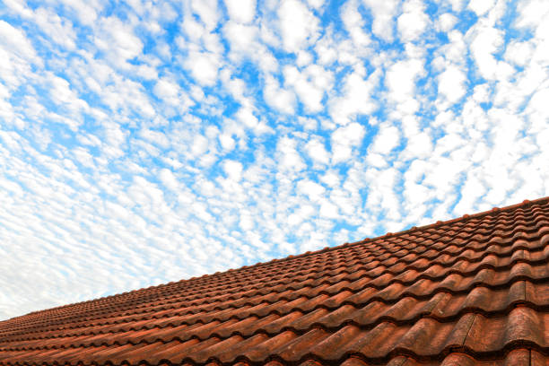 Red house roof and blue sky with white fluffy clouds