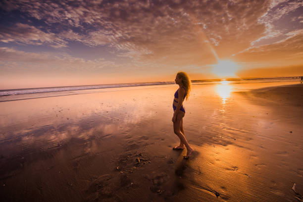 istock Woman walking on the beach at sunrise. 910918704