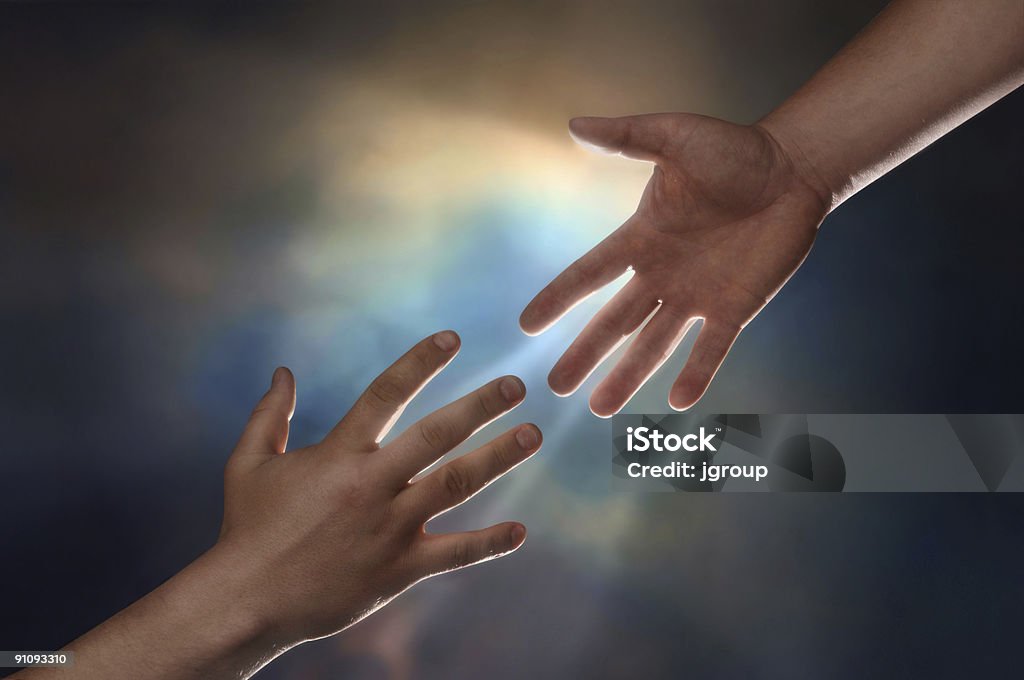 Two hands reaching for each other with a bright light Two male hands; one reaching down to assist another hand reaching up with sunburst in the background A Helping Hand Stock Photo