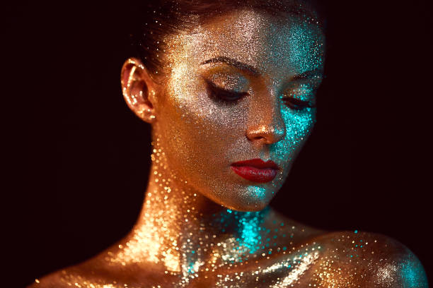 Portrait of beautiful woman with sparkles on her face Portrait of Beautiful Woman with Sparkles on her Face. Girl with Art Make-Up in Color Light. Fashion Model with Colorful Makeup body paint stock pictures, royalty-free photos & images