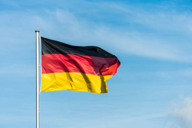 istock German flag waggling in the wind with sky in background 910943794
