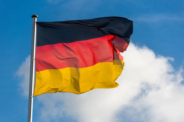 istock German flag waggling in the wind with blue sky 910944010