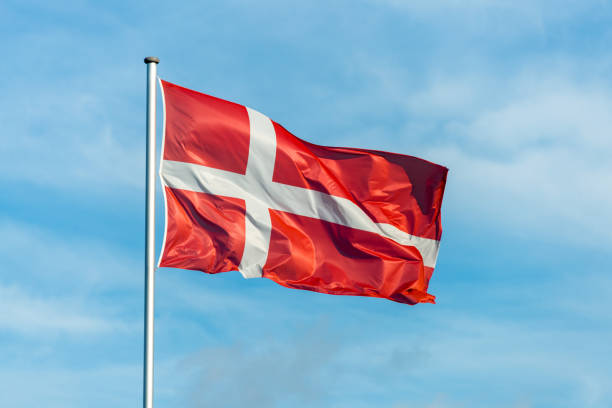 istock Danish flag waggling in the wind with sky in background 910945360