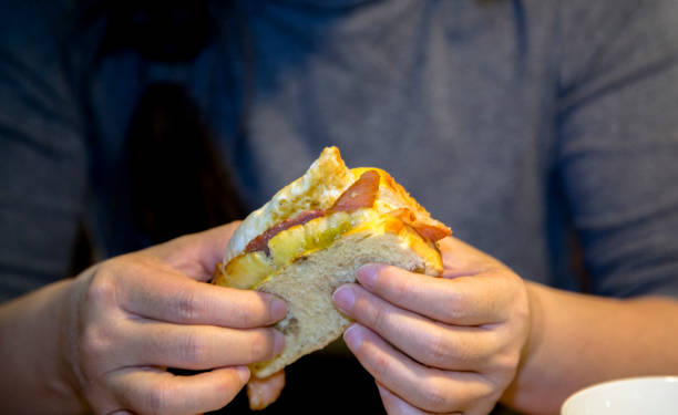 istock eating toasted bread, jammed with fried egg and bacon 910947550