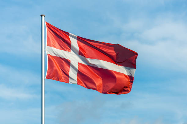 Danish flag waggling in the wind with sky in background Closeup of single danish flag waving in the wind in front of blue sky zealand denmark stock pictures, royalty-free photos & images