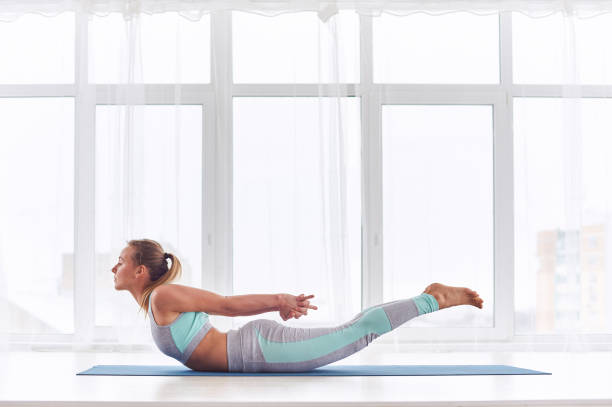 hermosa mujer prácticas yoga asana salabhasana - postura de langosta en el estudio de yoga - acostado boca abajo fotografías e imágenes de stock