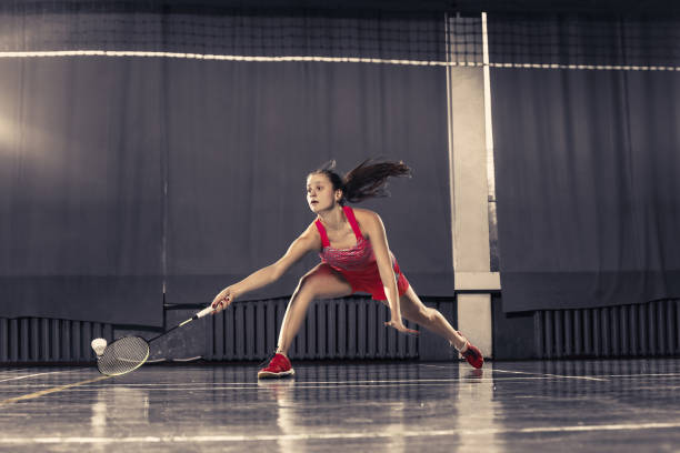istock Young woman playing badminton at gym 910967588