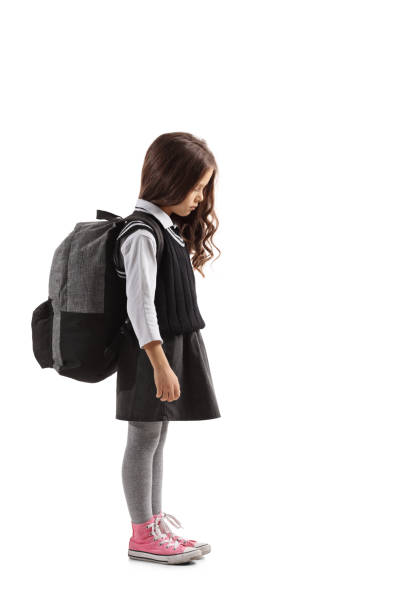 Sad little schoolgirl with a backpack Full length profile shot of a sad little schoolgirl with a backpack isolated on white background sad child standing stock pictures, royalty-free photos & images