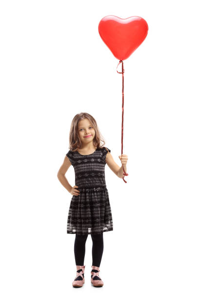 маленькая девочка, держащая воздушный шар в форме сердца - little girls pre adolescent child standing isolated стоковые фото и изображения