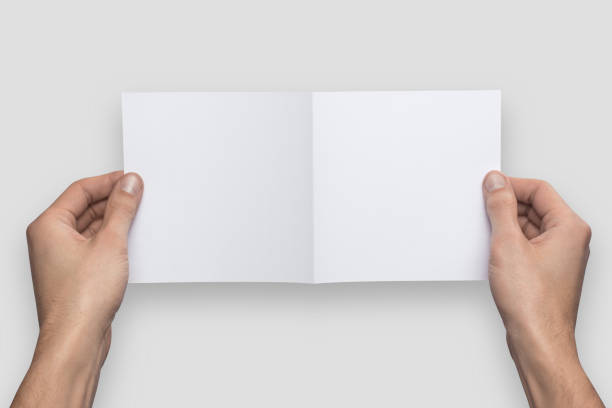 istock Mockup square empty blank bent in half white postcard holds the man in his hand. Isolated on a gray background 910990488