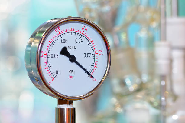 Pressure gauge on a blurry industrial background. Black and white toned image.