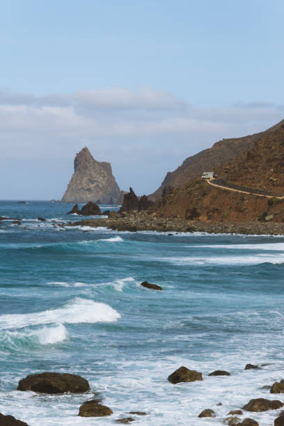 istock Remote road on coastline next to the beach with crashing waves 910995108