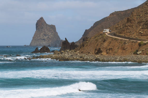 istock Remote road on coastline next to the beach with crashing waves 910995112