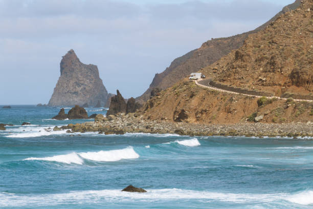 istock Remote road on coastline next to the beach with crashing waves 910995116