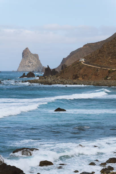 istock Remote road on coastline next to the beach with crashing waves 910995136