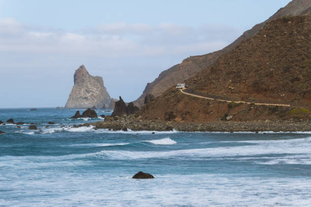 istock Remote road on coastline next to the beach with crashing waves 910995148
