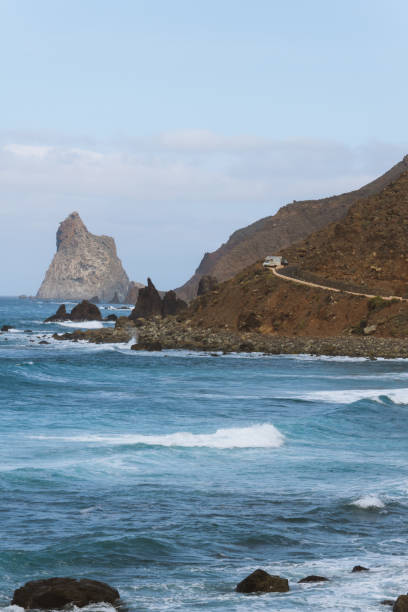 istock Remote road on coastline next to the beach with crashing waves 910995160