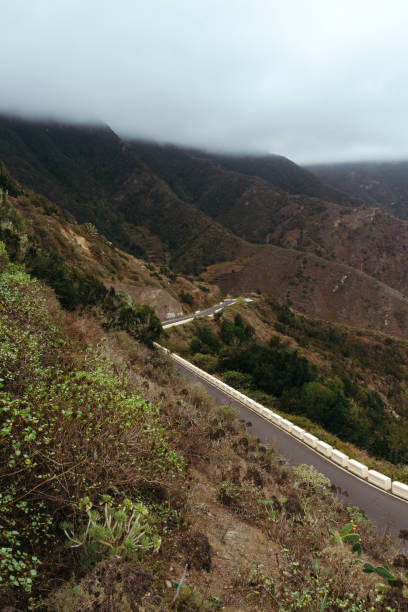 istock Empty road on hillside in mountains covered in clouds 910998296