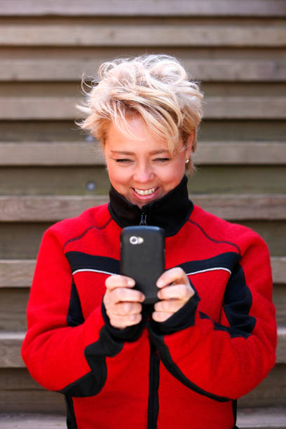 istock Attractive blond woman text messaging outdoors. 911007802