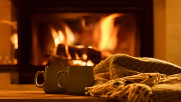 Photo of Steam from a cups with a hot cocoa on the fireplace background.