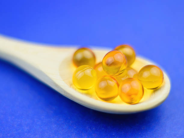 istock Fish oil capsules in spoon light wood against a blue background. Selective focus. 911014884
