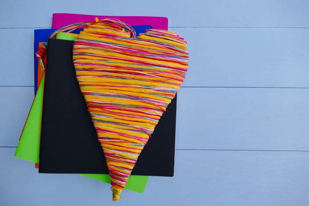 Colorful notebooks and a colorful heart lying on top