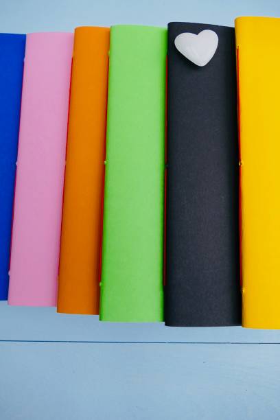 Colorful notebooks in a row and a white heart lying on black book