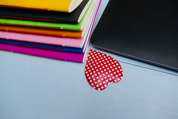 istock Colorful paper notebooks and a laptop, pluse red heart shape 911022670