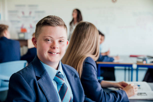 Schoolboy in Class Headshot of down syndrome teenage boy during a lesson. school boy in uniform stock pictures, royalty-free photos & images