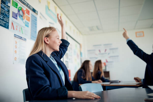 Any Questions Teenage female student raising her hand to answer a question. teenage high school girl raising hand during class stock pictures, royalty-free photos & images