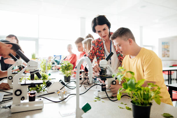 Learning in the Laboratory Down syndrome boy at school, learning in the laboratory with a microscope, teacher assisting. special education stock pictures, royalty-free photos & images