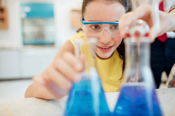 Chemistry Experiment Low angle view of female high school student in chemistry class, pouring chemicals into a flask. chemistry class stock pictures, royalty-free photos & images
