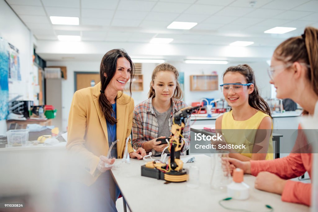 Studying Robotic Arm Point of view angle of teenage girls studying robotic arm in school. Education Stock Photo