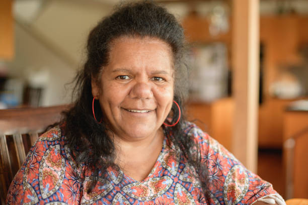 Mature Aboriginal woman looking at camera and smiling Head and shoulders shot of woman in her 50s with cheerful expression aborigine woman stock pictures, royalty-free photos & images