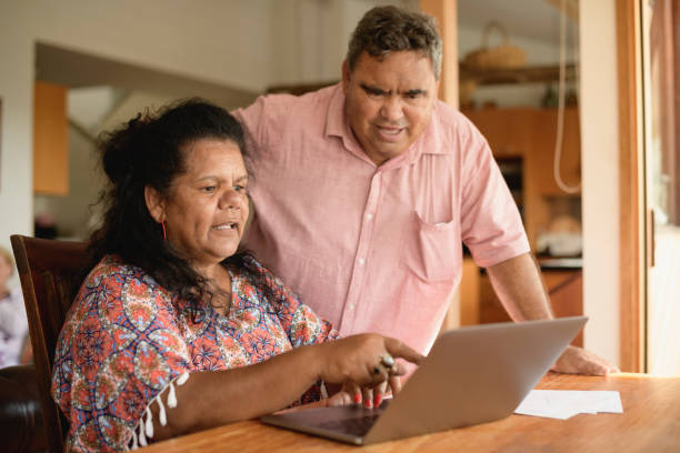 зрелая пара с помощью ноутбука с женщиной указывая - австралийские аборигены стоковые фото и изображения