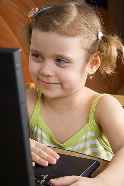 little girl working with a laptop stock photo