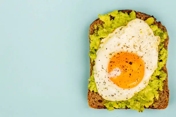 Photo of Fried Egg Sunny Side Up on Crushed Avocado And Rye Bread Open Faced Sandwich