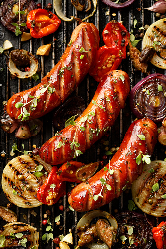 Grilled sausages and vegetables with addition spices and fresh herbs, top view