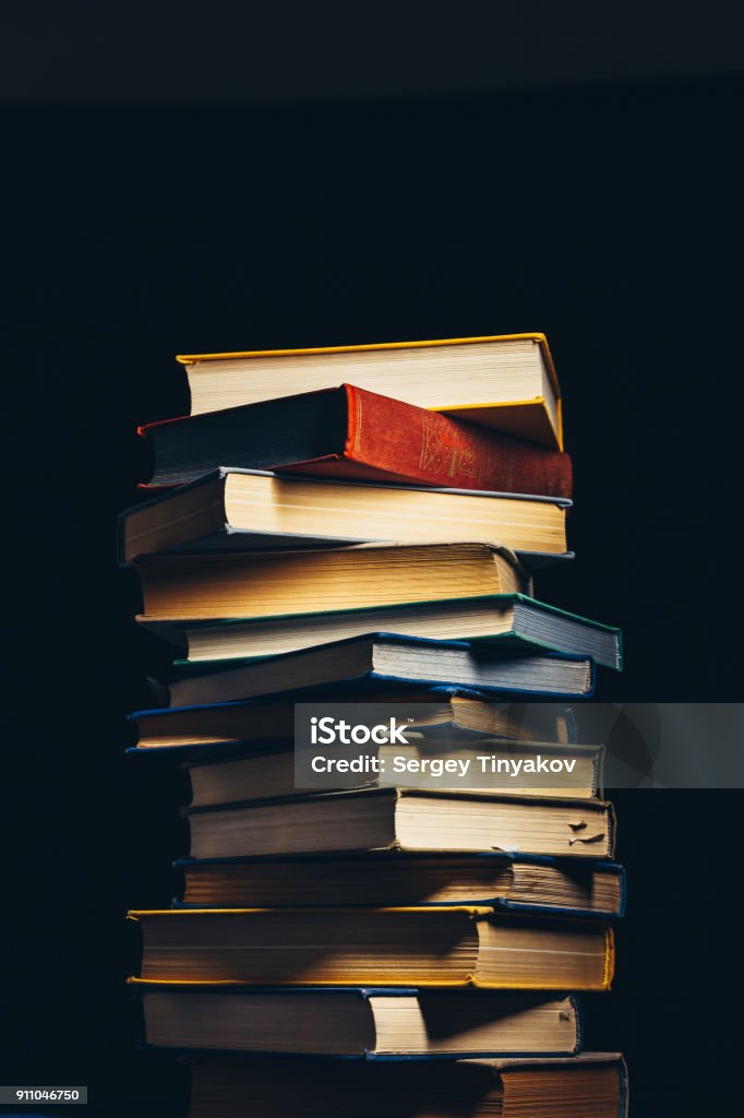 Tower Of Old Multi-colored Books On A Black Background. Concept Of Education And Knowledge Tower Of Old Multi-colored Books On A Black Background Book Stock Photo