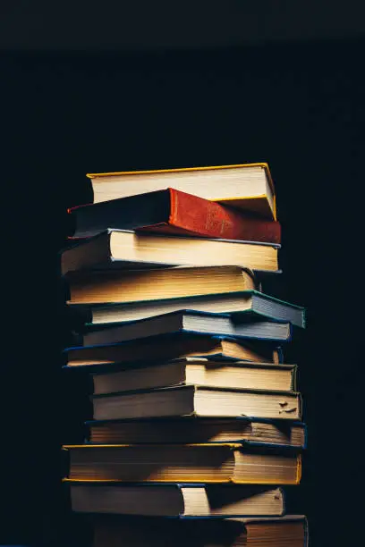 Photo of Tower Of Old Multi-colored Books On A Black Background. Concept Of Education And Knowledge