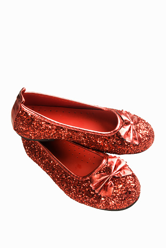 One pair of small red colored glittered slipper type shoes on a white background.