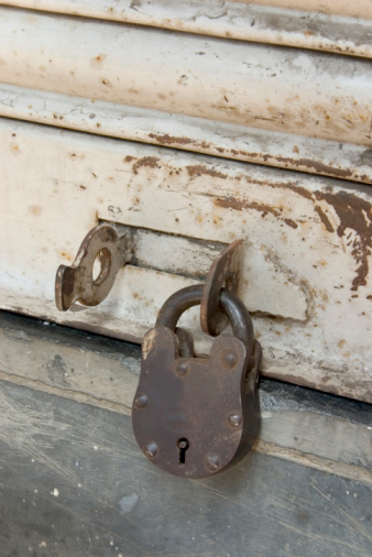 Locked old red double door with rusty padlock. Peeled door