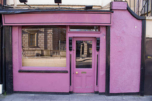 People walking past a window of a shop closing down on a busy high street in Ilford on a rainy day. March 2023