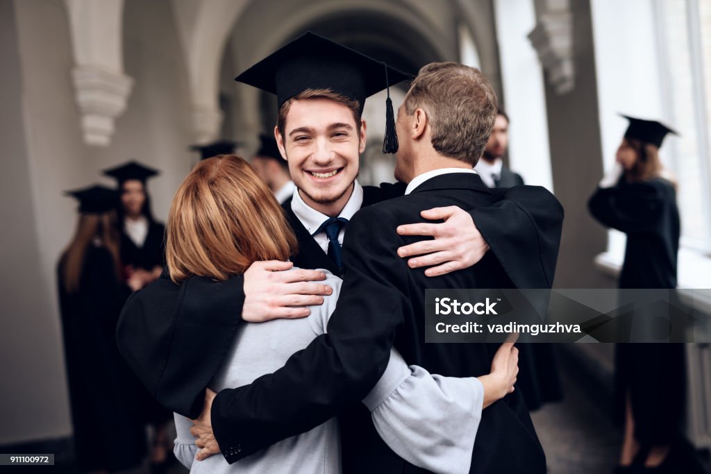 Parents congratulate the student, who finish their studies at the university. Parents congratulate the student, who finish their studies at the university. He graduates. They are very happy about this. Graduation Stock Photo