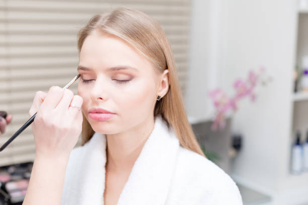 istock Paint eyes. Makeup artist creating beautiful makeup for blondes model. Beauty and Spa centre concept 911109034