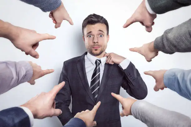 Photo of Many fingers pointing at a businessman